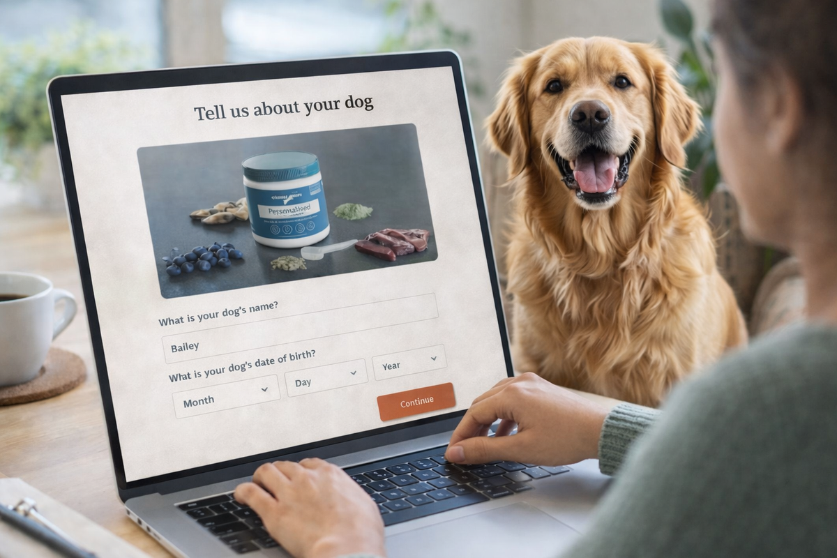 Person using a laptop with a dog sitting next to them, on a table.
